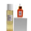 Marula Green Beauty Glow Reset Toner and Fade Face Oil displayed together in an elevated product arrangement, with the toner standing beside a white pedestal and the orange-tinted face oil positioned on top, against a clean white background.