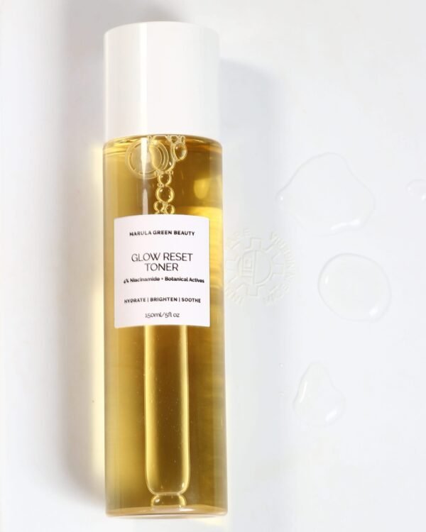 Marula Green Beauty Glow Reset Toner bottle filled with golden toner, photographed against a white background with visible bubbles and droplets of toner beside it.